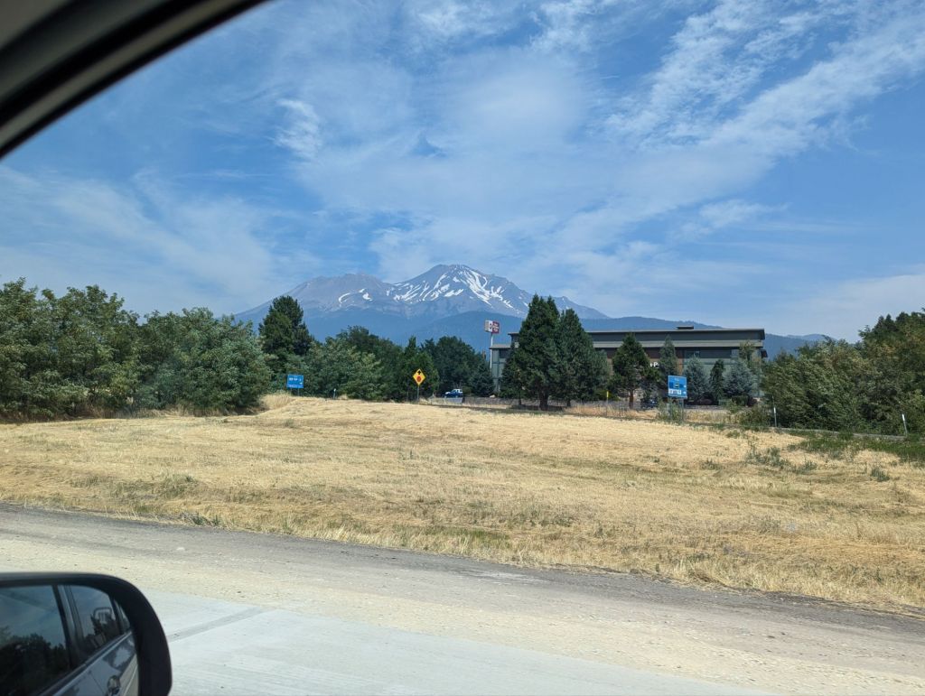 View on Mount Shasta dring down the freeway from a car window. There is still abot of snow on the peak.