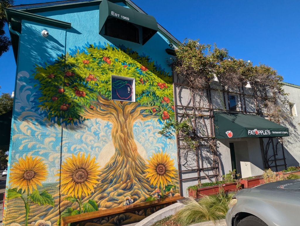 Wall mural of an apple tree and sun flowers on a house wall.
